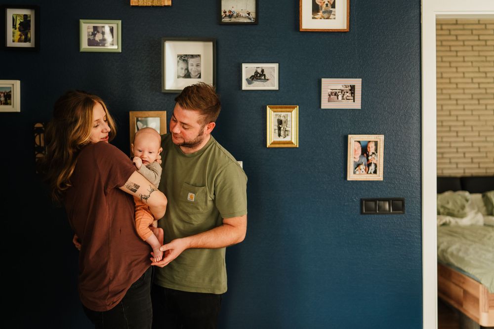 A heartwarming family scene against a navy blue wall decorated with framed photos.