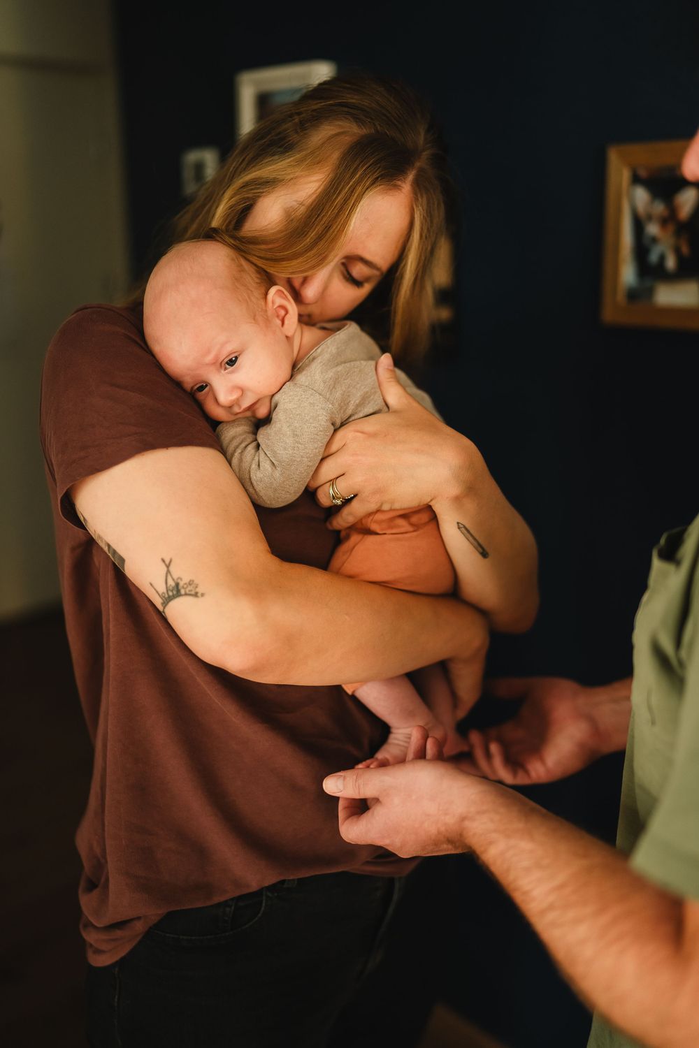 A tender embrace captured in a home setting with dark blue walls and photo frames.