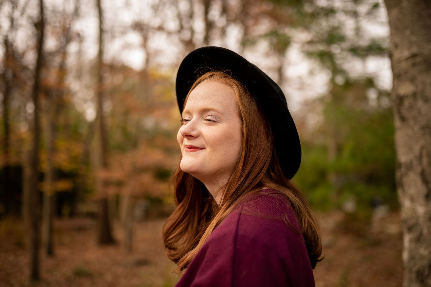Red head wearing a hat posing in the fall foliage