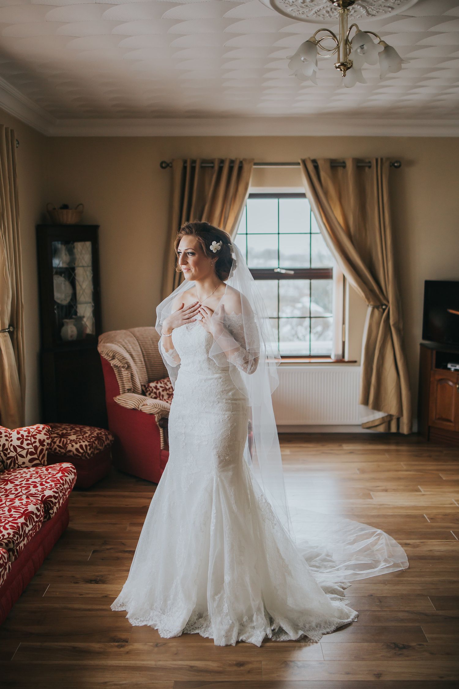 Wedding dress preparations in a spacious room with warm lighting and elegant curtains.