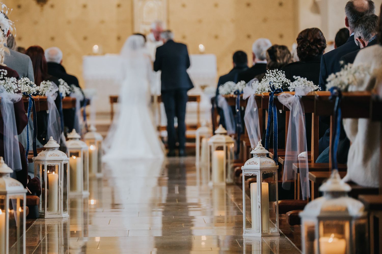 Elegant wedding aisle lined with lanterns and candles in a church setting.