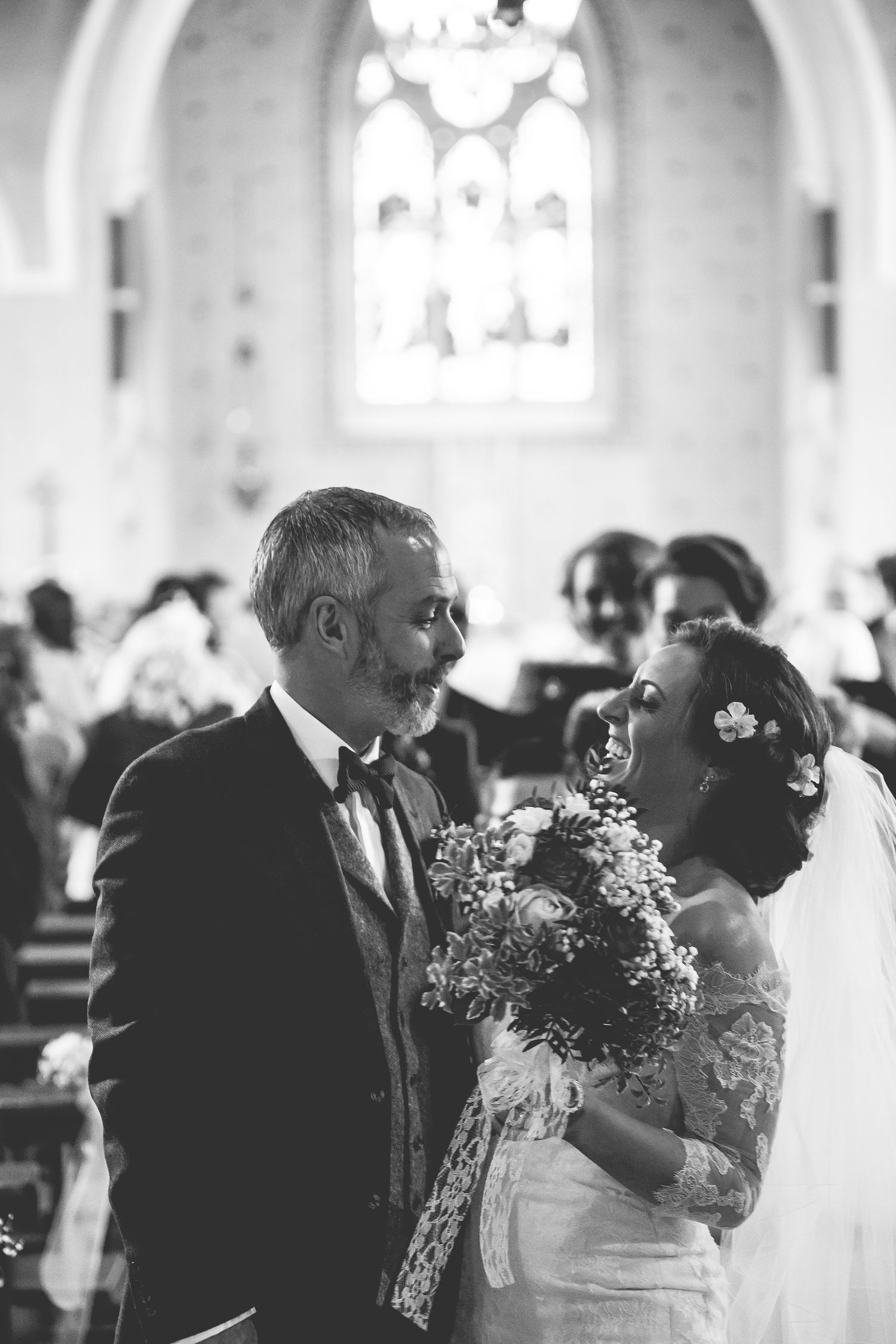 Black and white church wedding ceremony with soft window light.