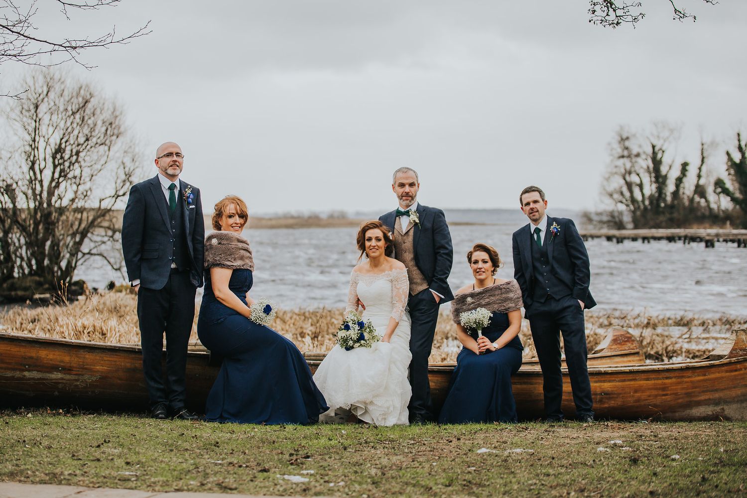 Wedding party and couple pose for group photos in scenic outdoor setting.
