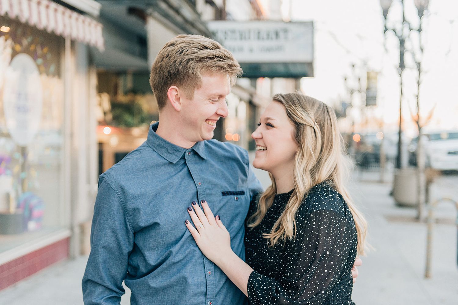 Couple shares tender moment outside storefront in matching blue tones.