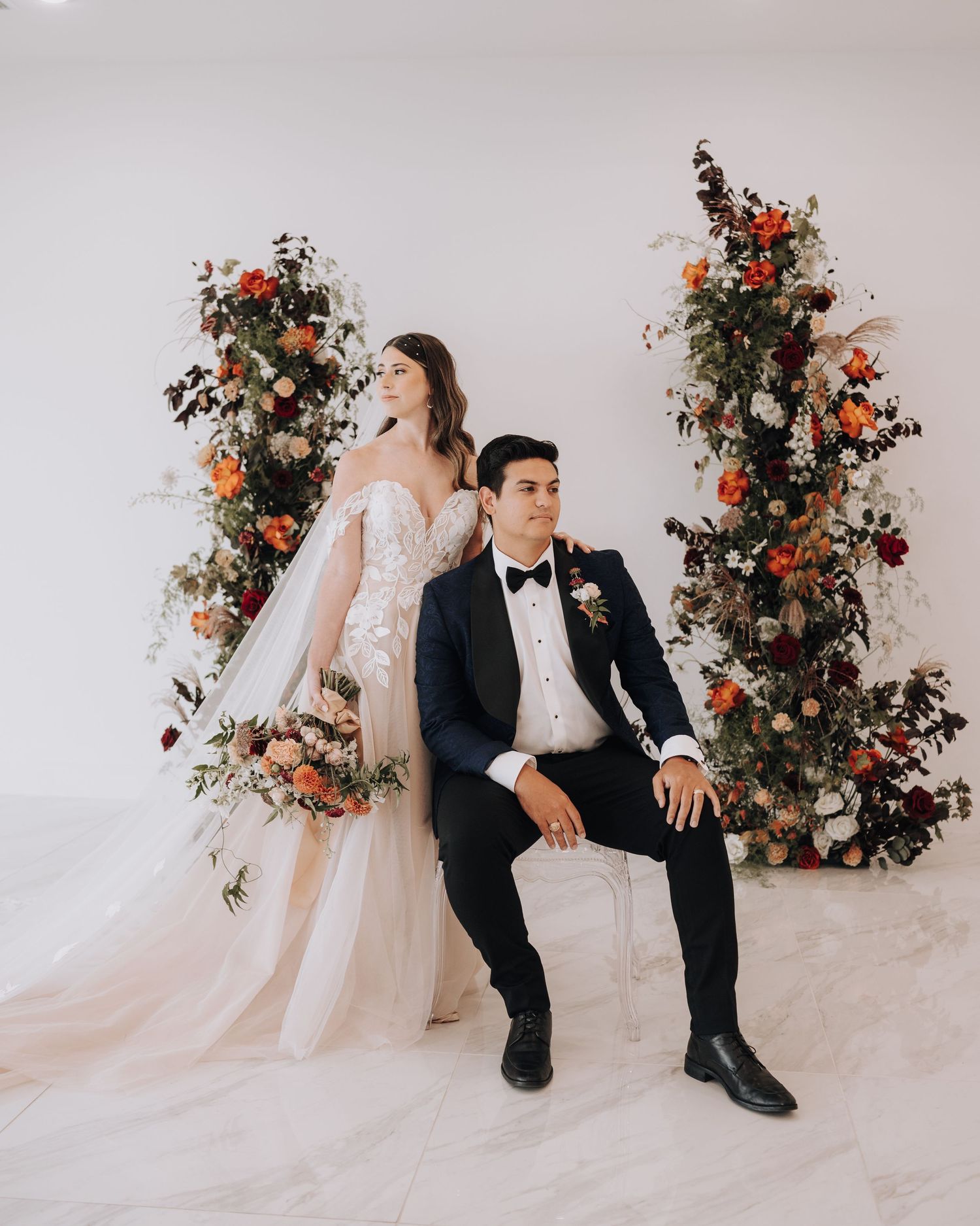 Stylish wedding portrait with floral arrangements featuring orange and white blooms.