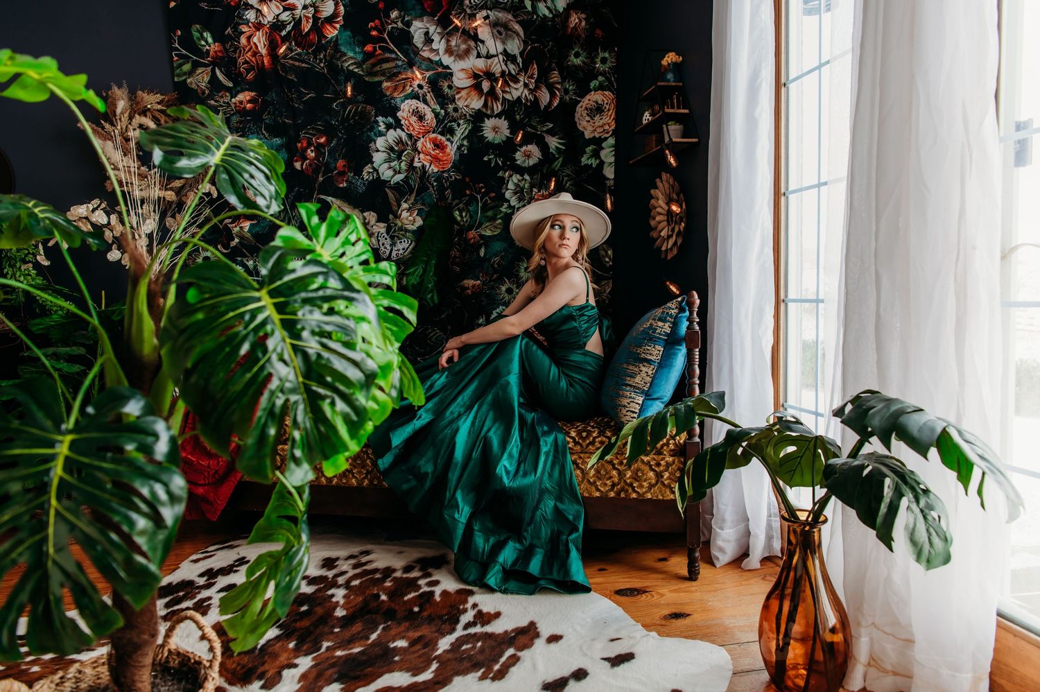 Emerald dress swirling in motion among tropical plants and floral wallpaper.
