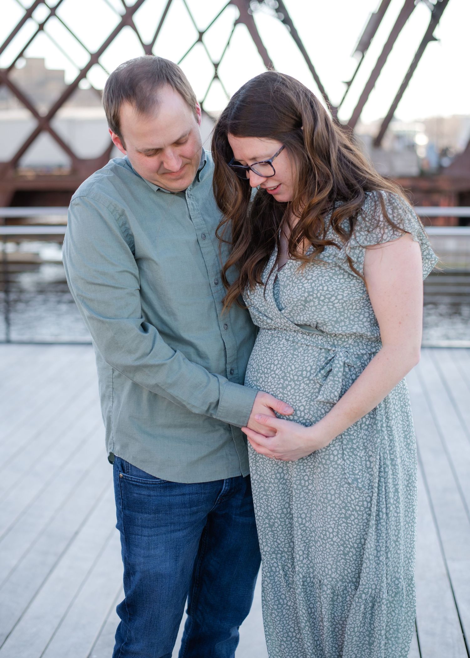 Couple sharing tender moment on wooden deck overlooking water.
