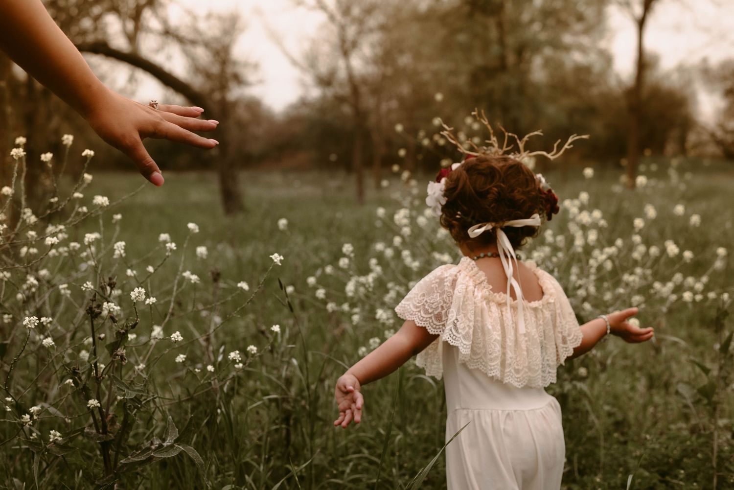 Playful moment of a child in white dress dancing among wildflowers.