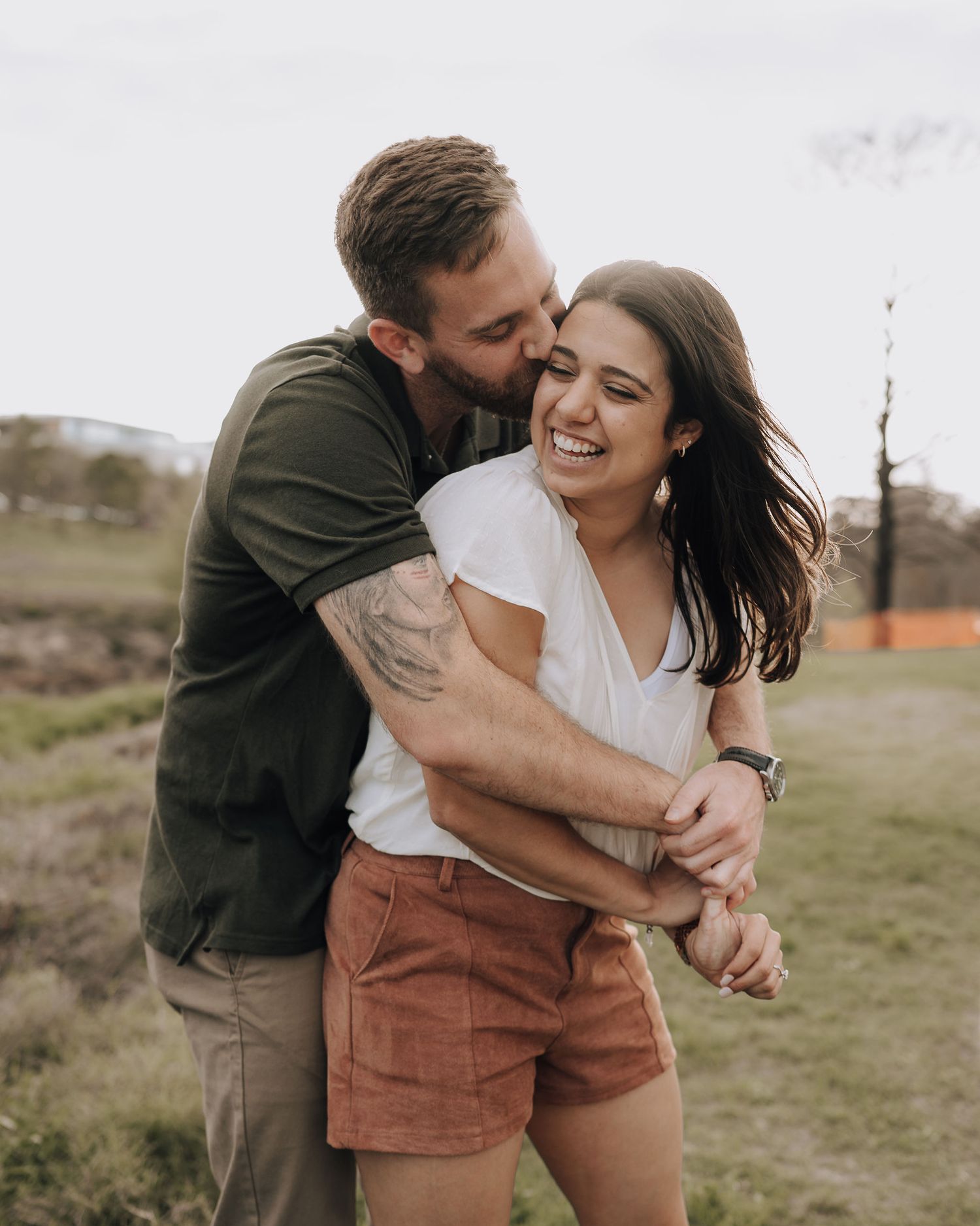 A couple embraces and laughs together during their outdoor engagement session.
