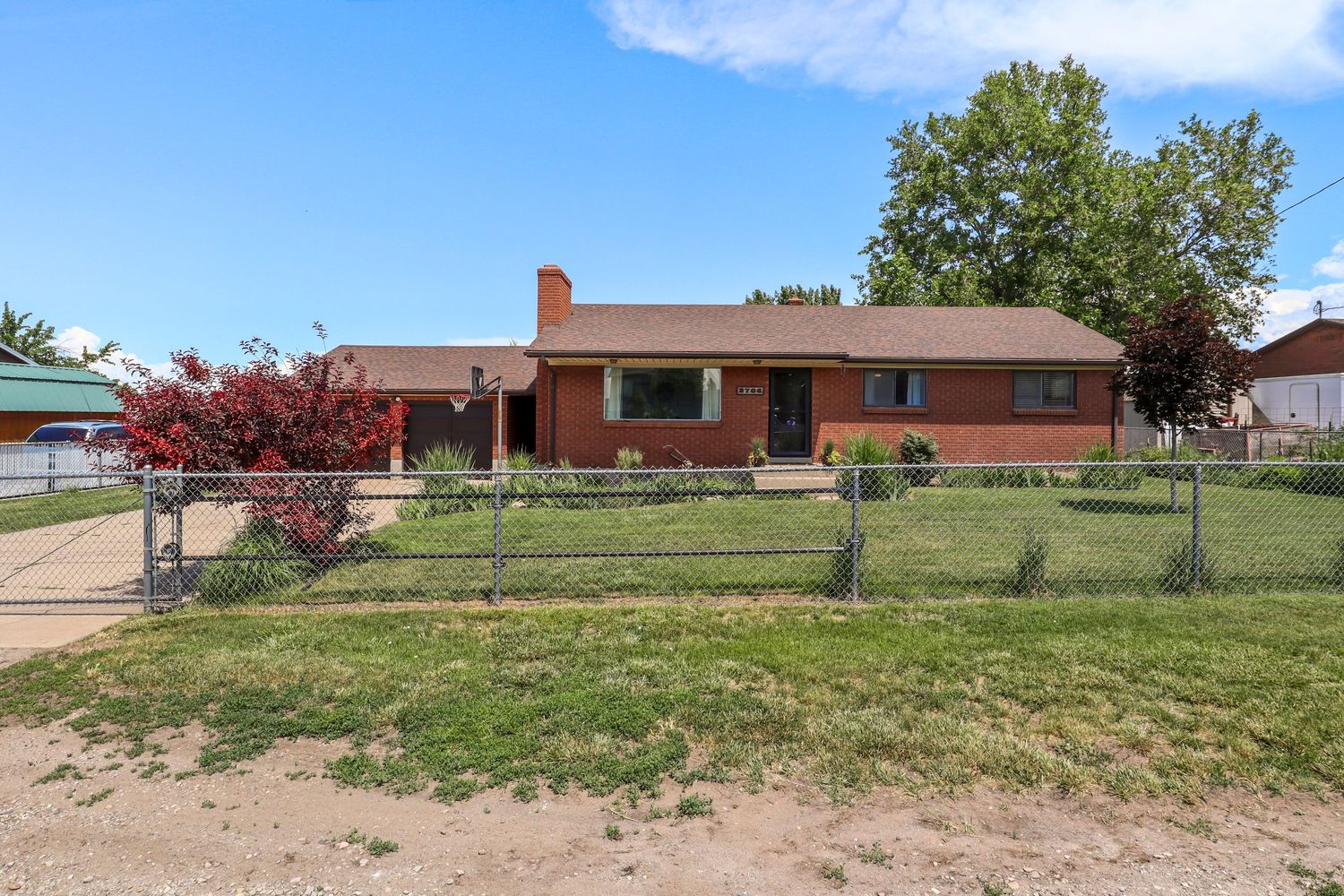 Brick ranch-style home with a fenced yard, mature trees, and a welcoming front entrance.