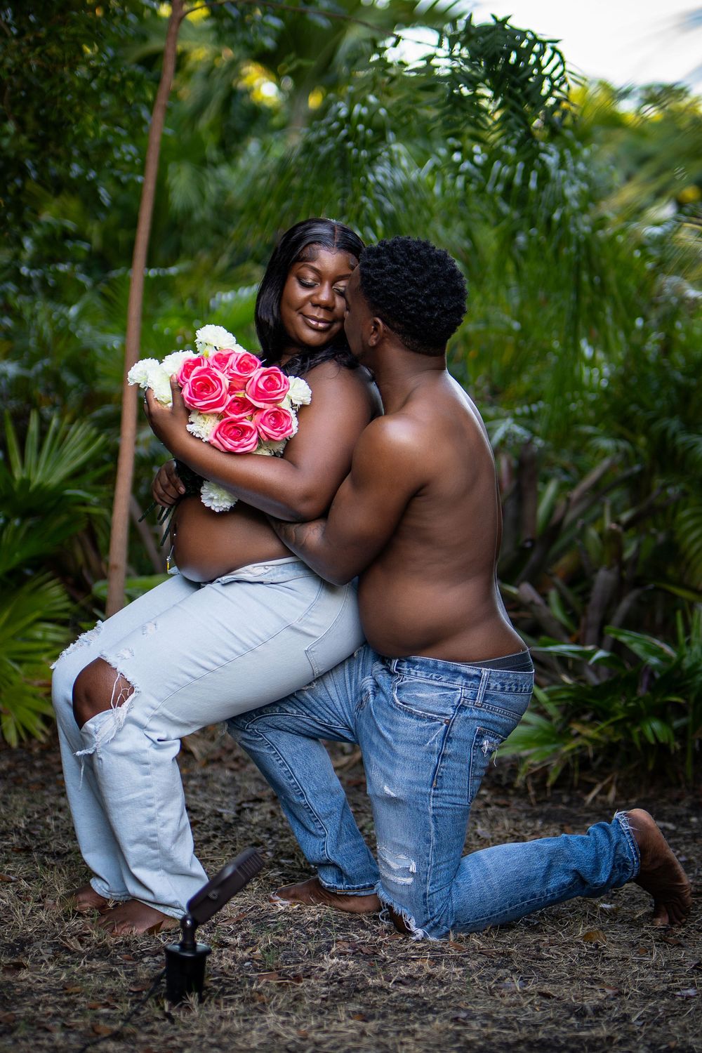 couple with pink flowers posing among greenery — tropical lifestyle portrait by Timoy B Photography in Antigua.