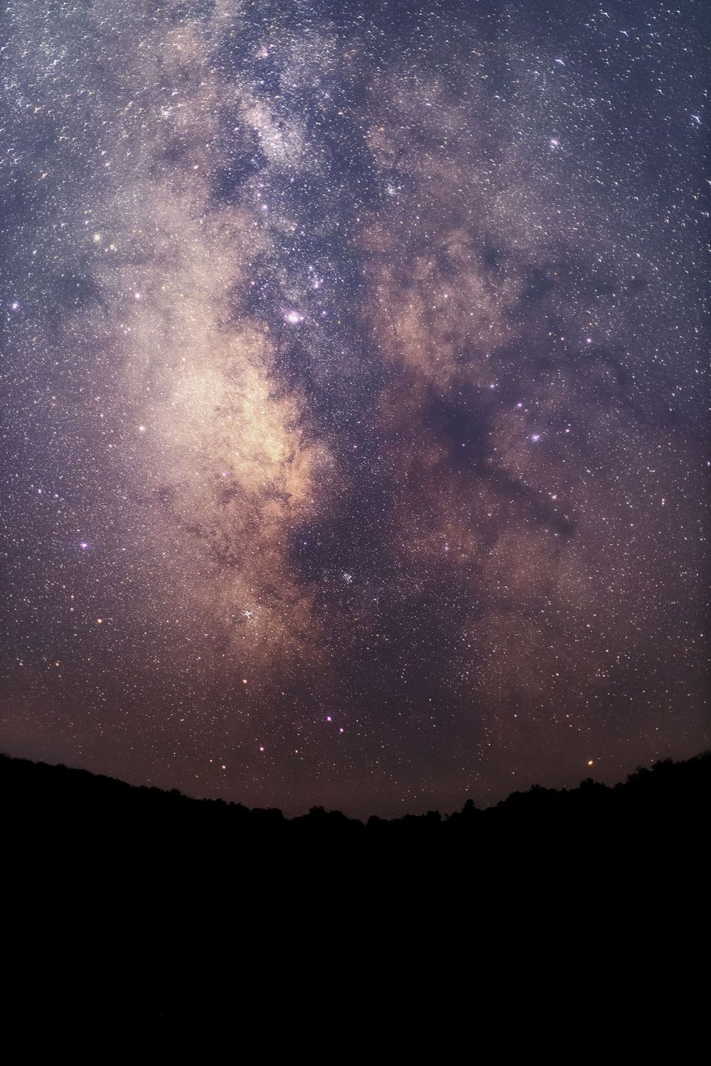 Stunning view of the Milky Way galaxy with purple and brown hues against a dark night sky.