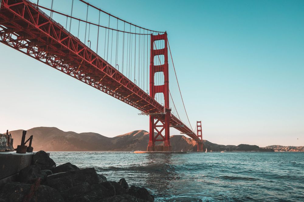 Golden Gate Bridge spans across San Francisco Bay under clear blue skies.