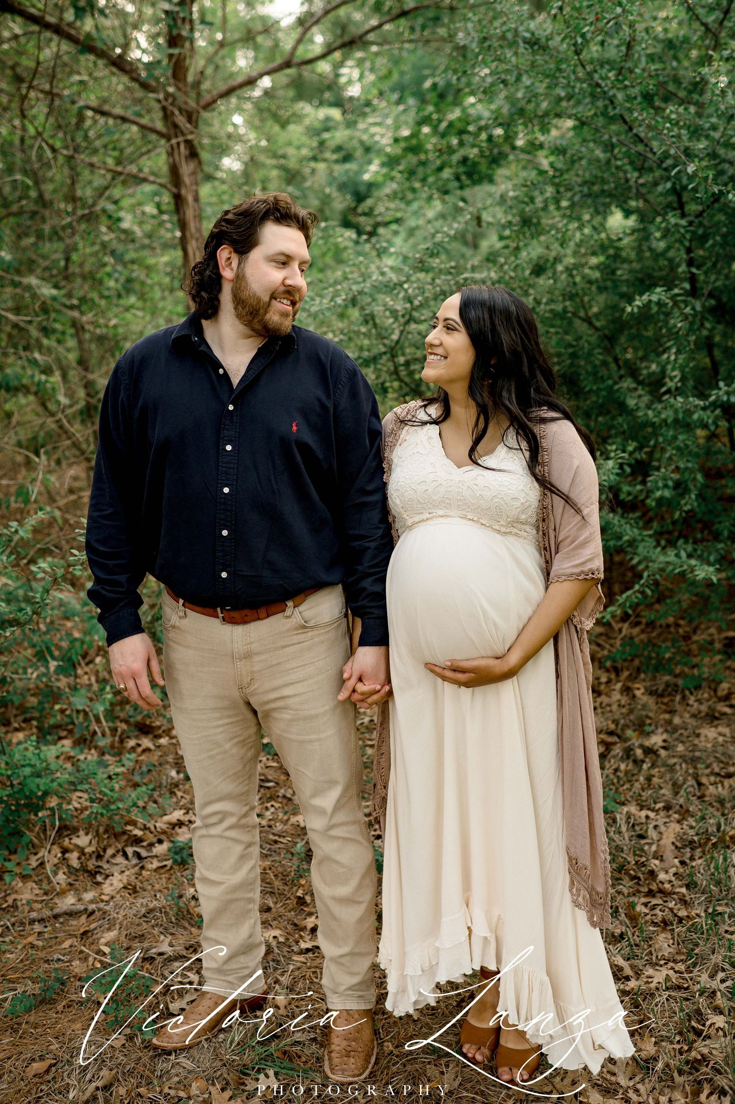 Romantic maternity portrait in a wooded setting with natural lighting.