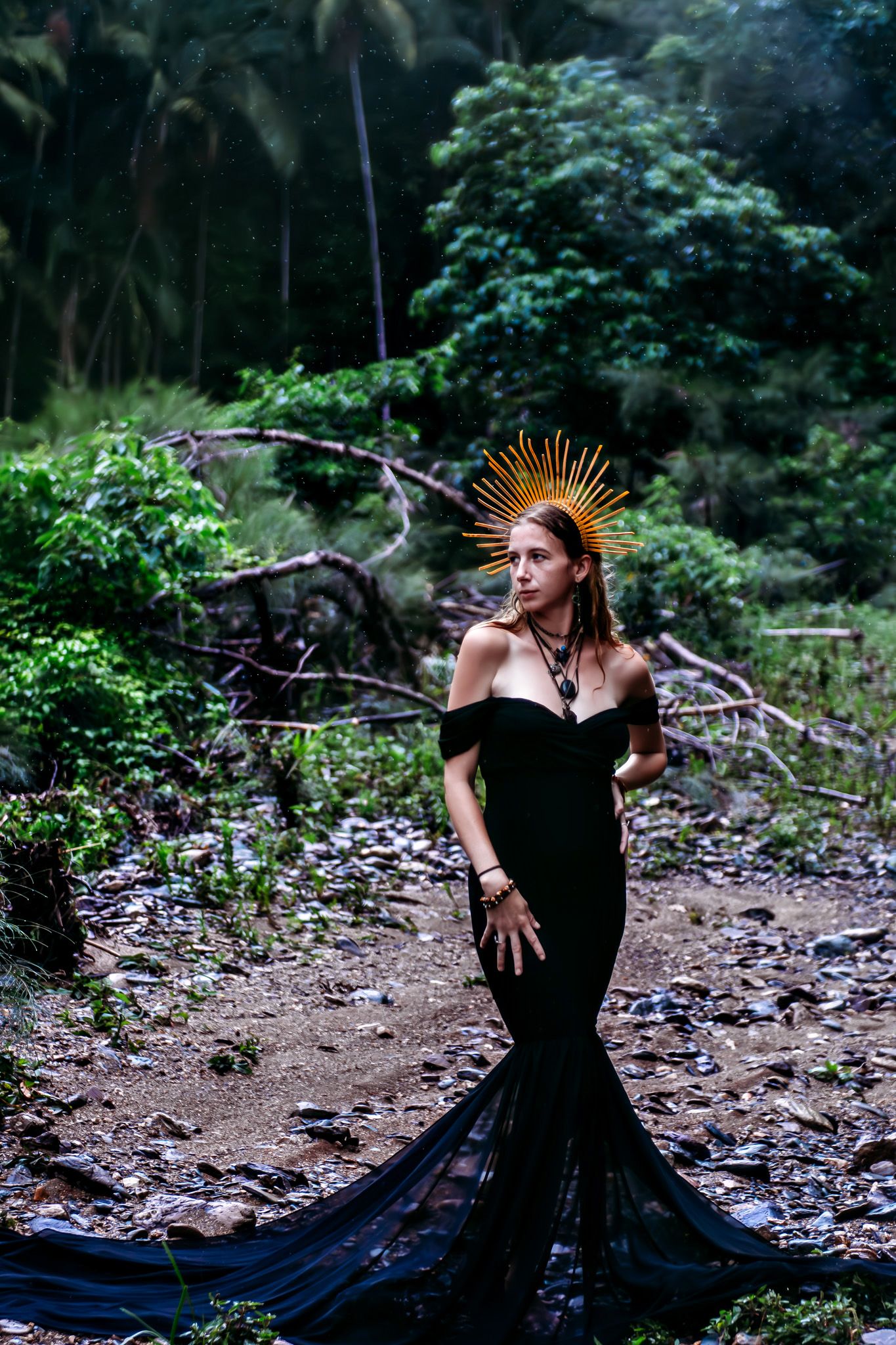 Artistic dance performance in black dress with gold crown in mystical forest setting.