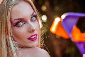 Close-up portrait with vibrant makeup against colorful bokeh lights.