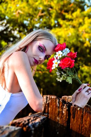 Artistic composition with red roses against wooden fence during sunset.