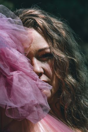 Romantic portrait with pink tulle fabric in natural lighting.