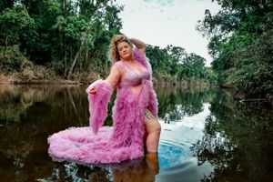 Fashion portrait in a flowing pink gown standing in shallow water.
