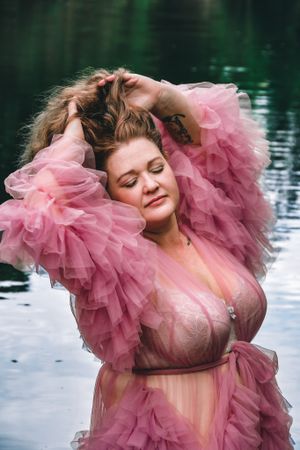 Ethereal fashion photo featuring pink tulle gown against reflective water backdrop.