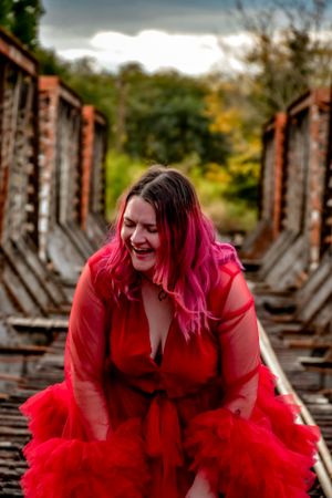 Fashion shoot featuring a vibrant red tulle dress on vintage railroad tracks.