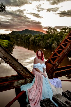 Ethereal fashion shoot on a bridge with pastel gowns during sunset.