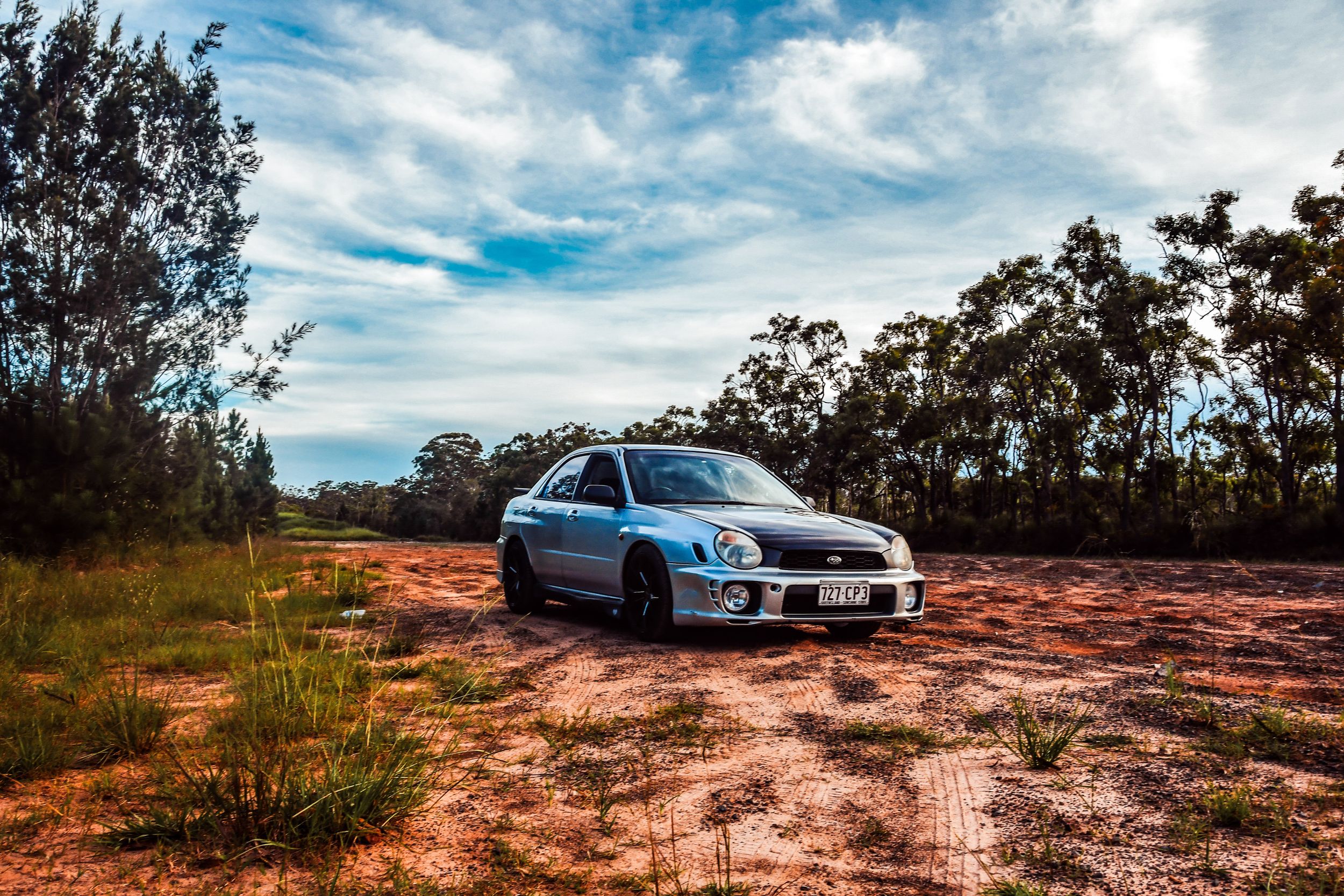 Silver Subaru WRX STI photographed against dramatic sky and red soil landscape.