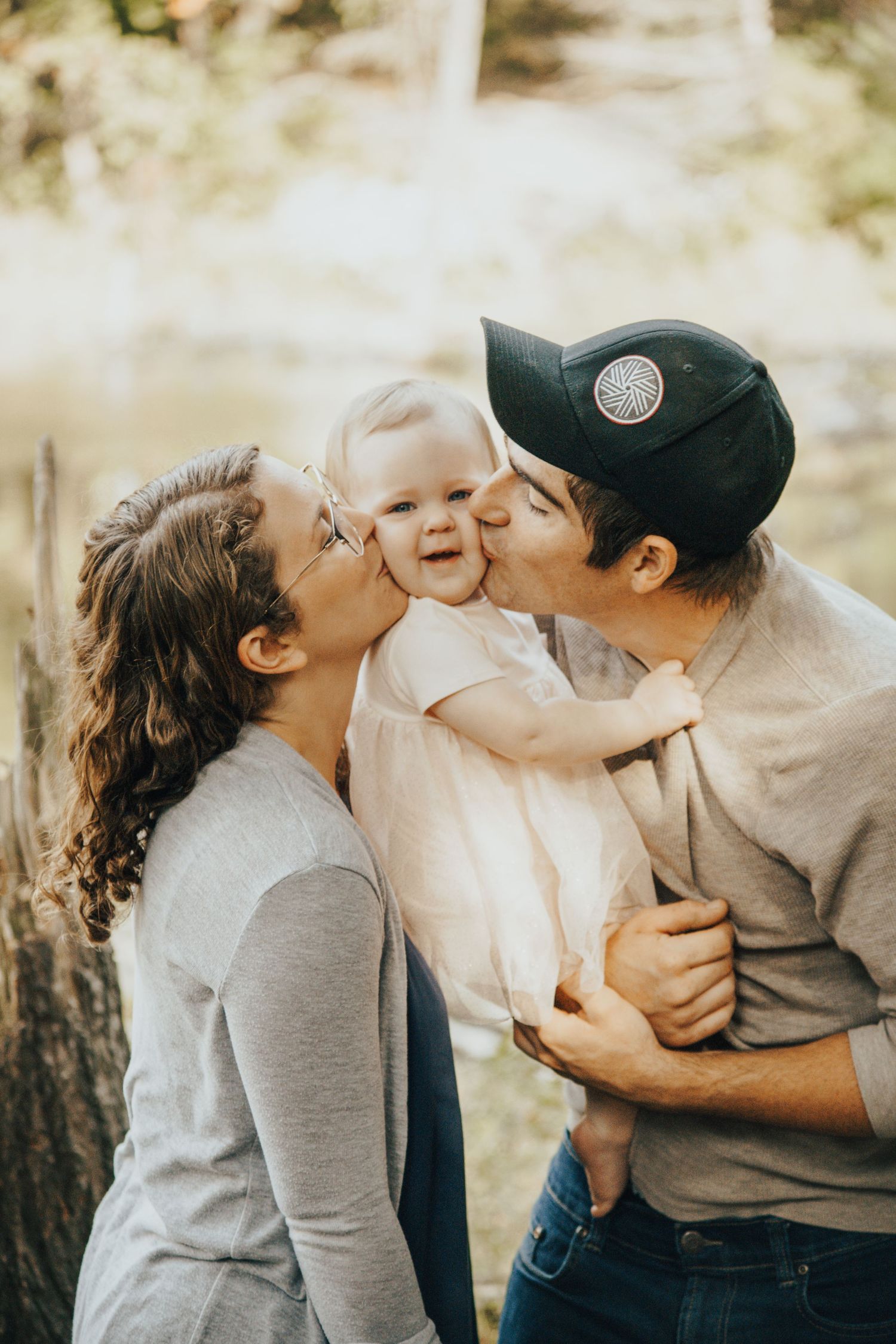 Image of parents kissing baby's cheeks.