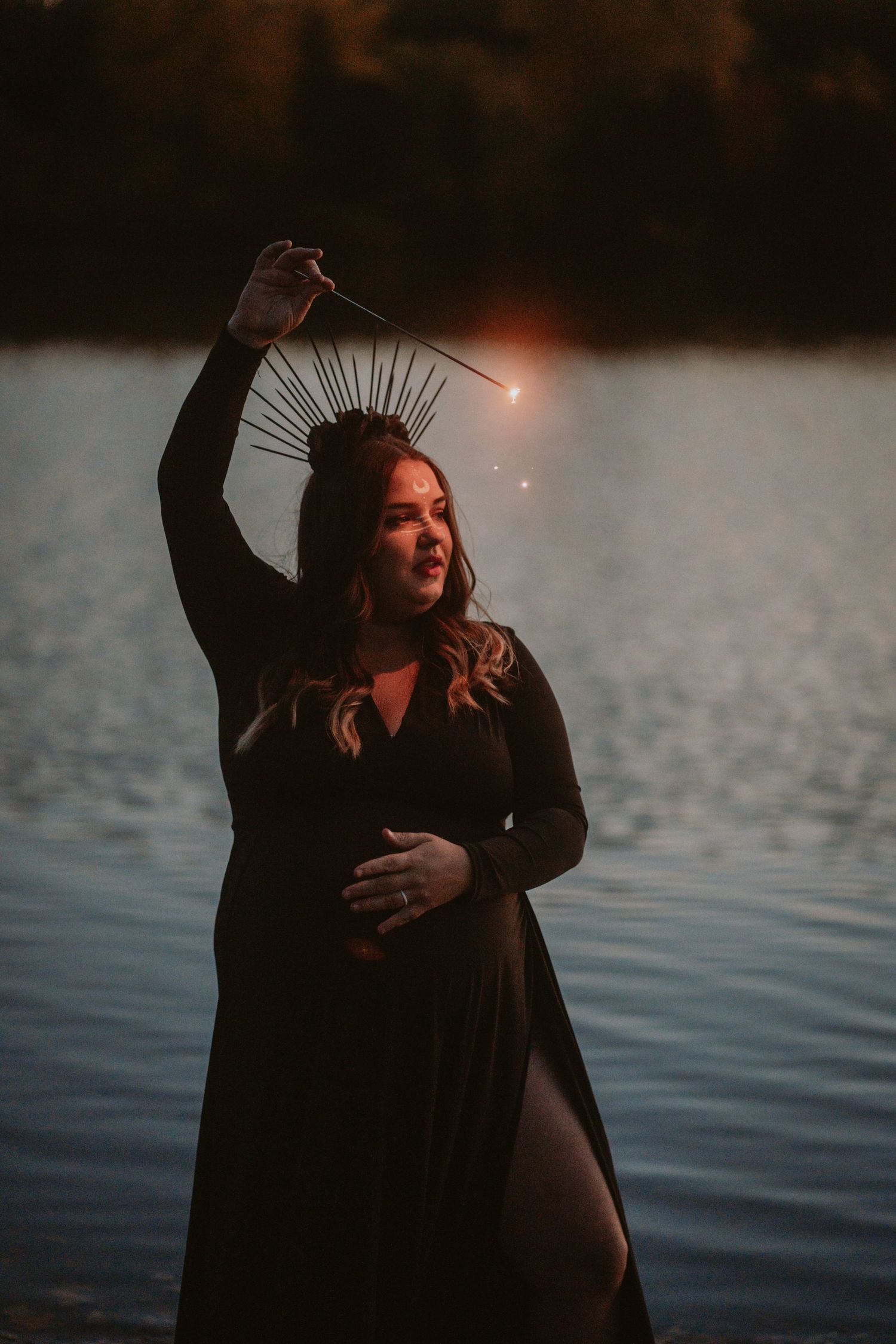 Image of woman with sparkler in front of water.
