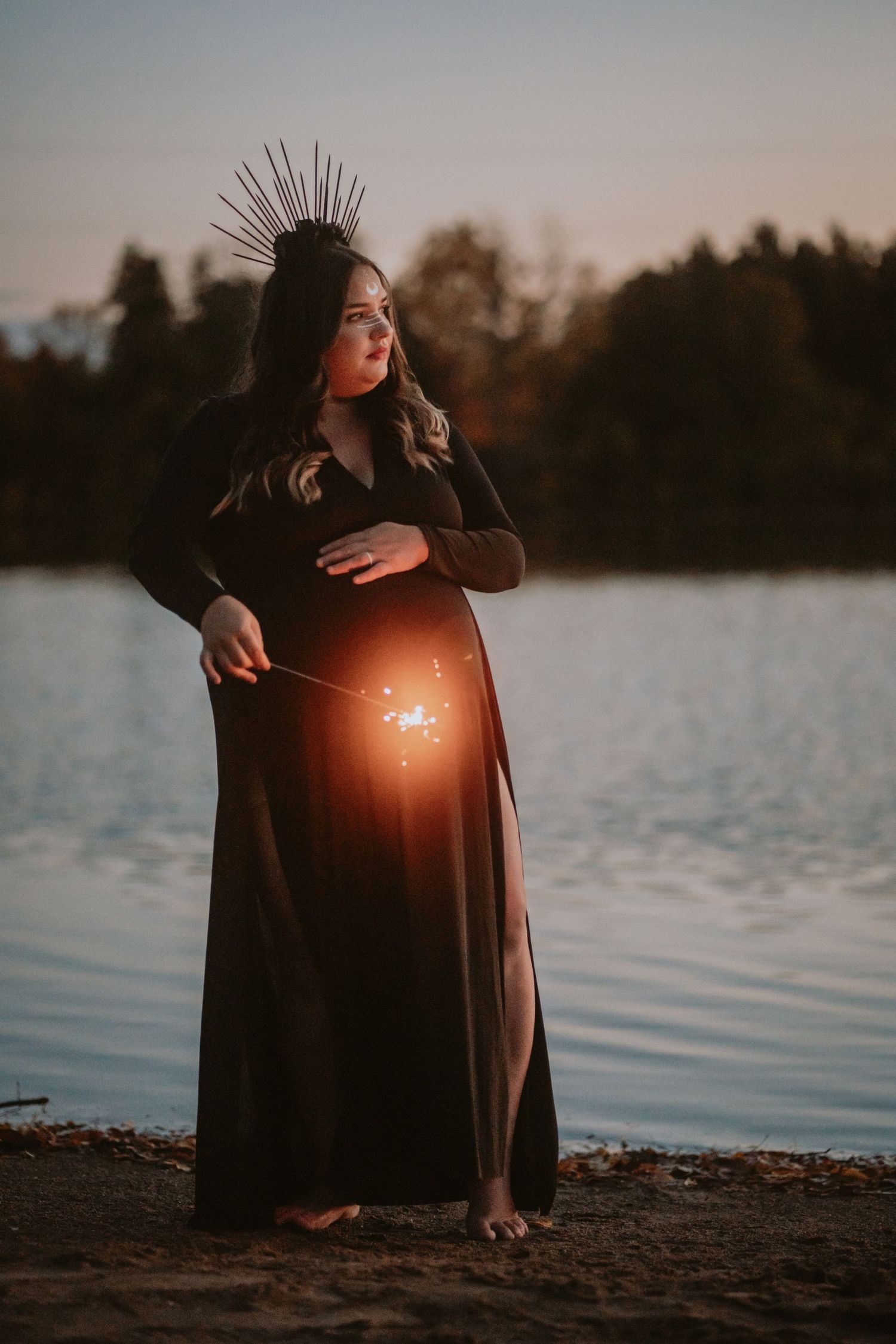 Image of woman with sparkler in front of water.