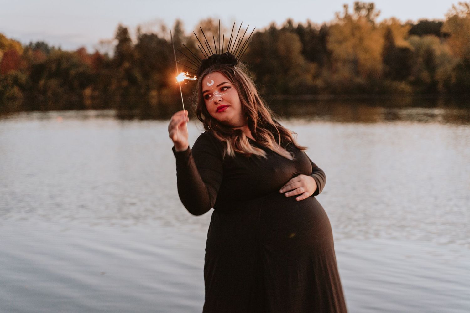 Image of woman with sparkler in front of water.