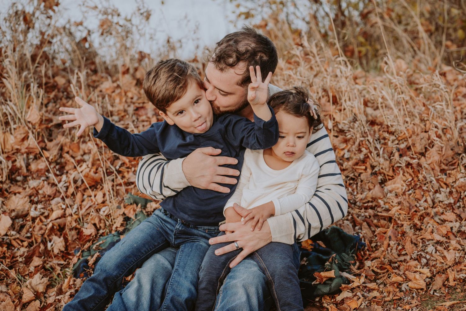 Image of dad and children in front of water.
