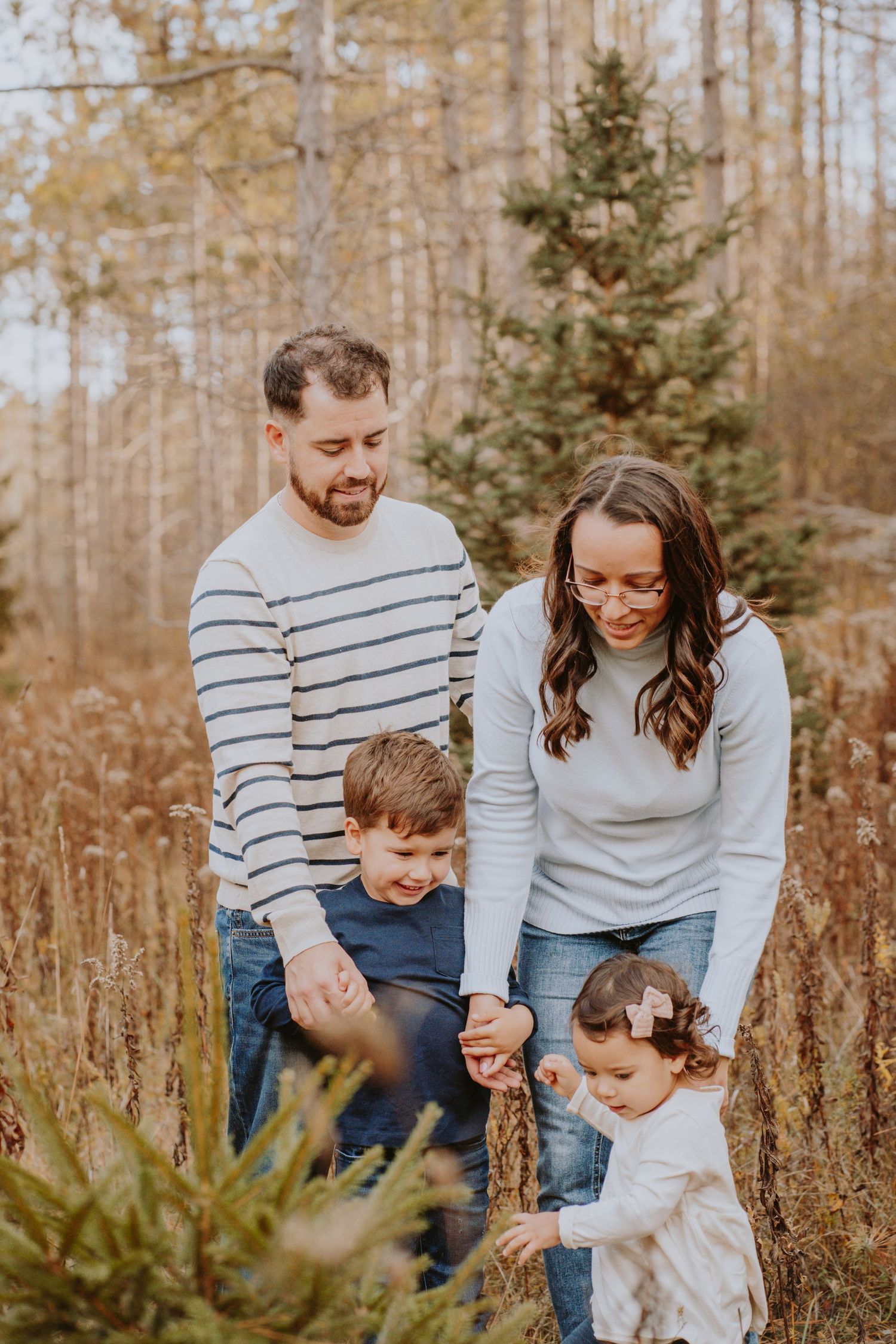 Image of family standing in field in front of trees.