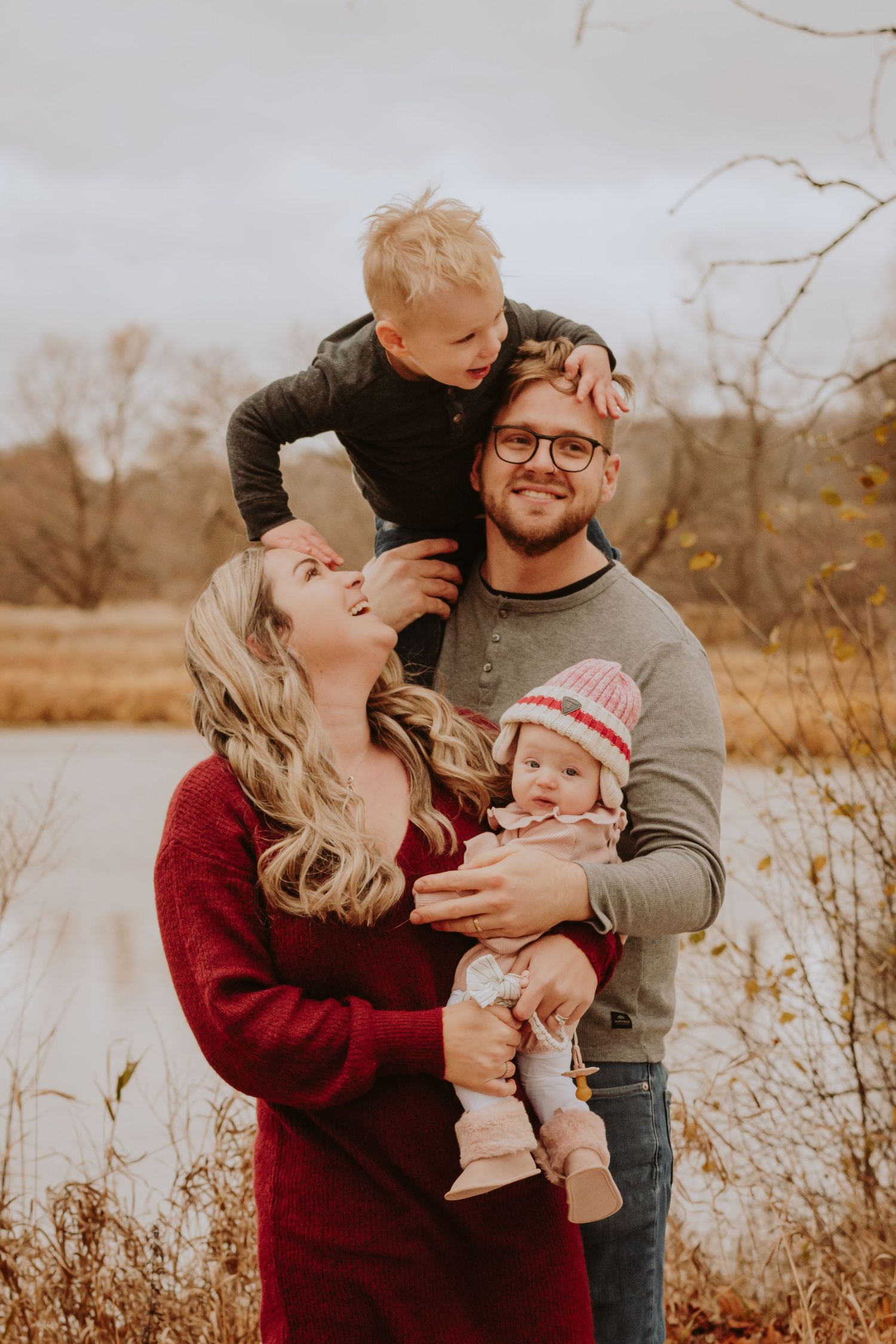 Image of family in front of water with child on shoulders.