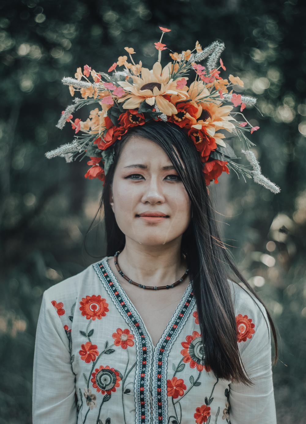 Person wearing an intricate coral and white floral crown with embroidered traditional dress.