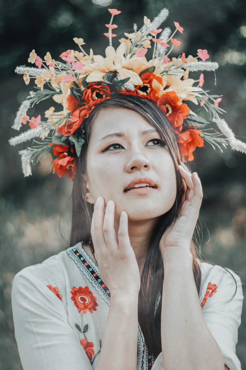 Person wearing an elaborate coral and white floral crown against a blurred forest background.