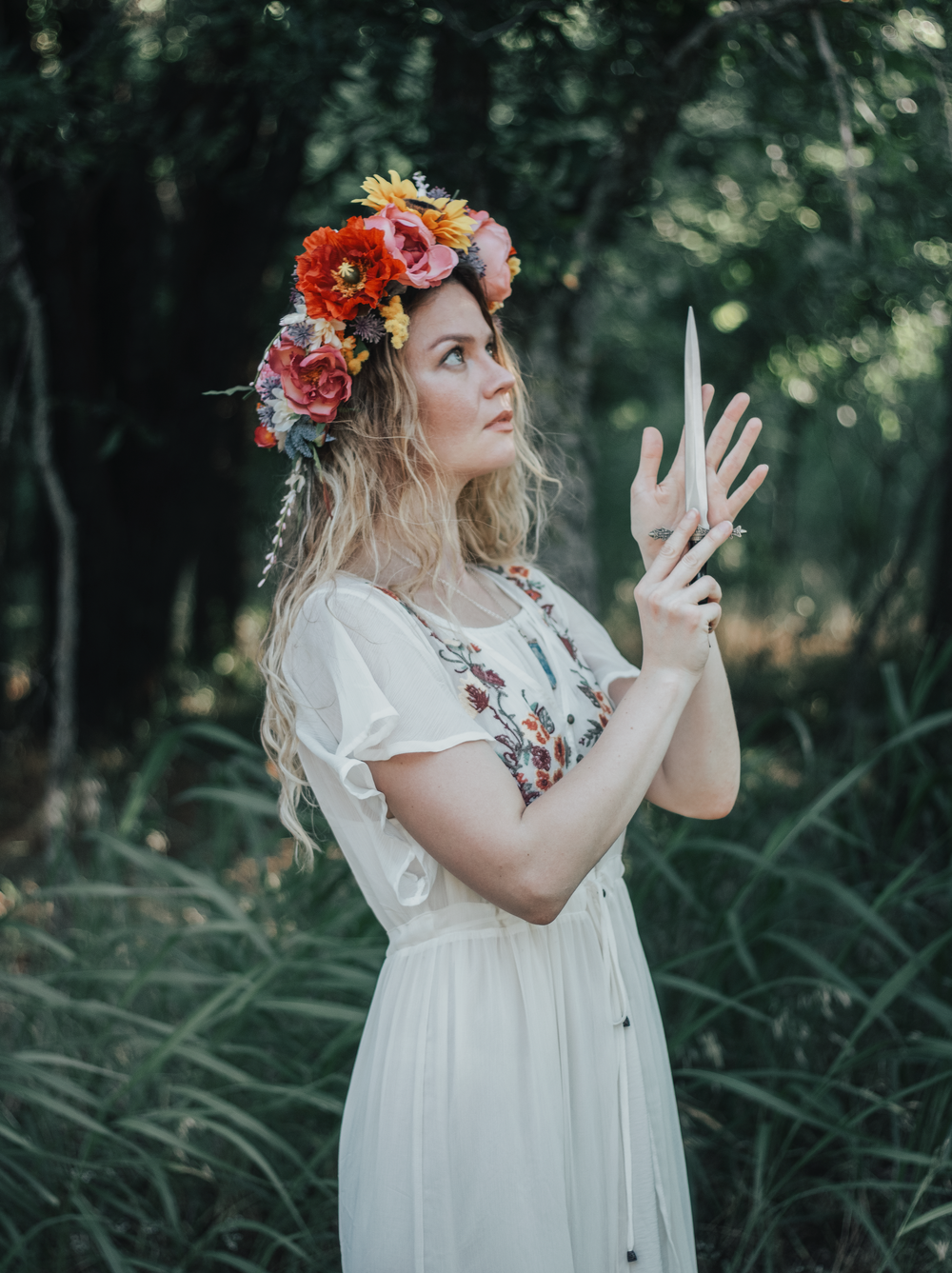 Ethereal forest photoshoot featuring white dress, floral embellishments and dramatic flower crown pose.