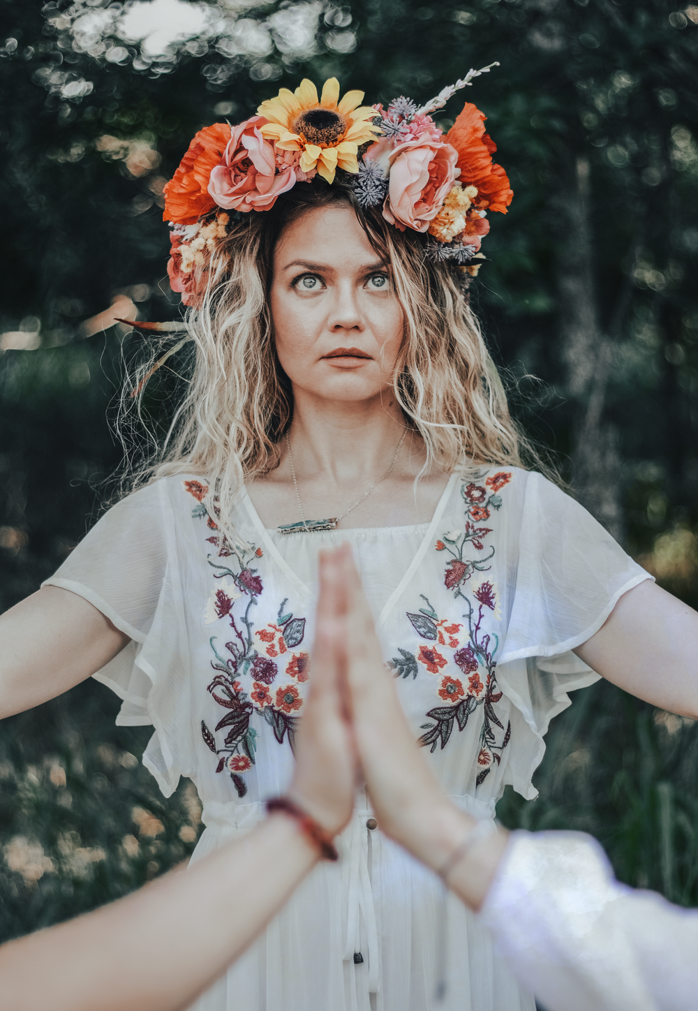 Artistic outdoor portrait with sunflower and rose crown against dark forest background.
