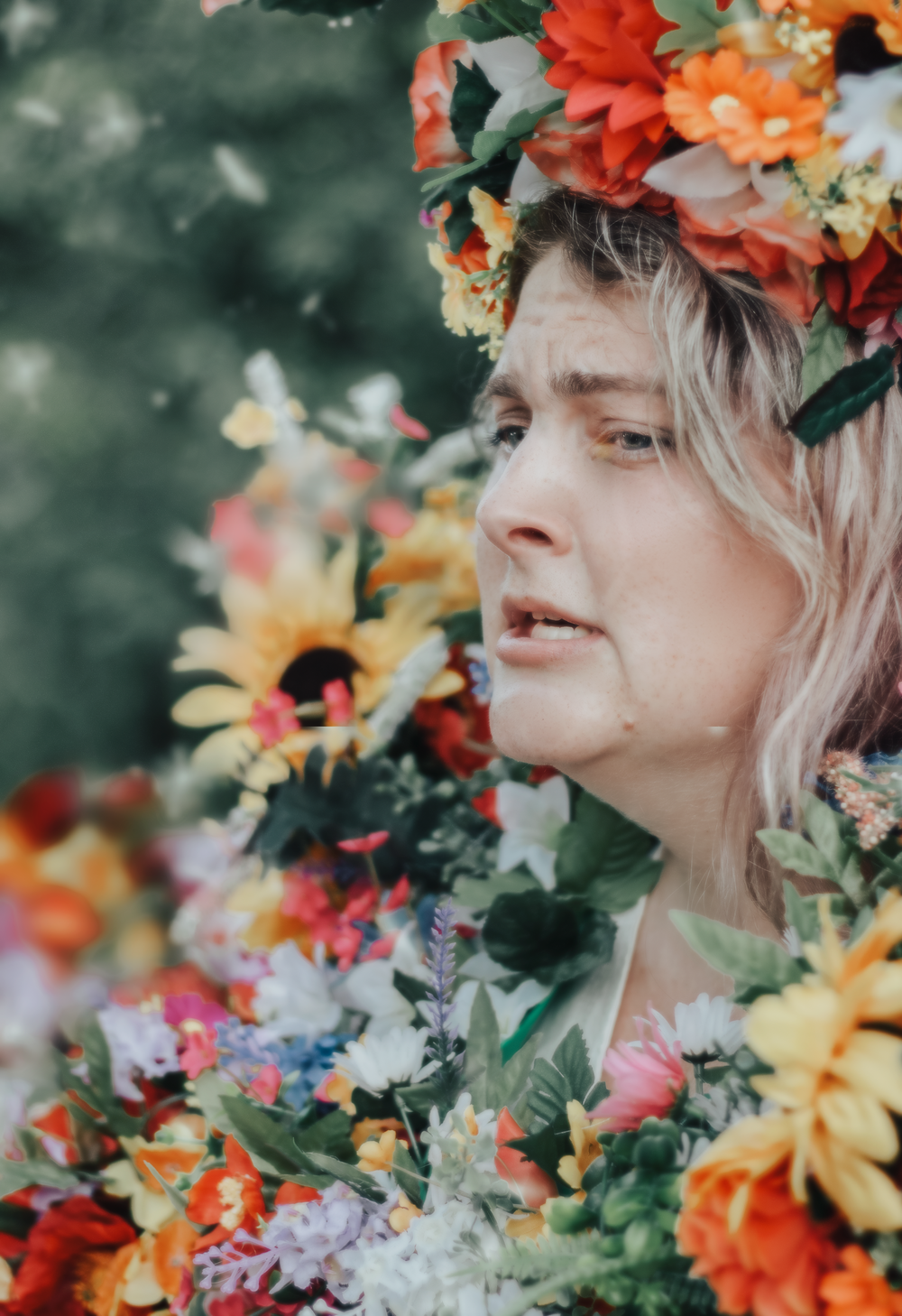 A dreamy side profile portrait with sunflowers and orange blooms in a floral crown.