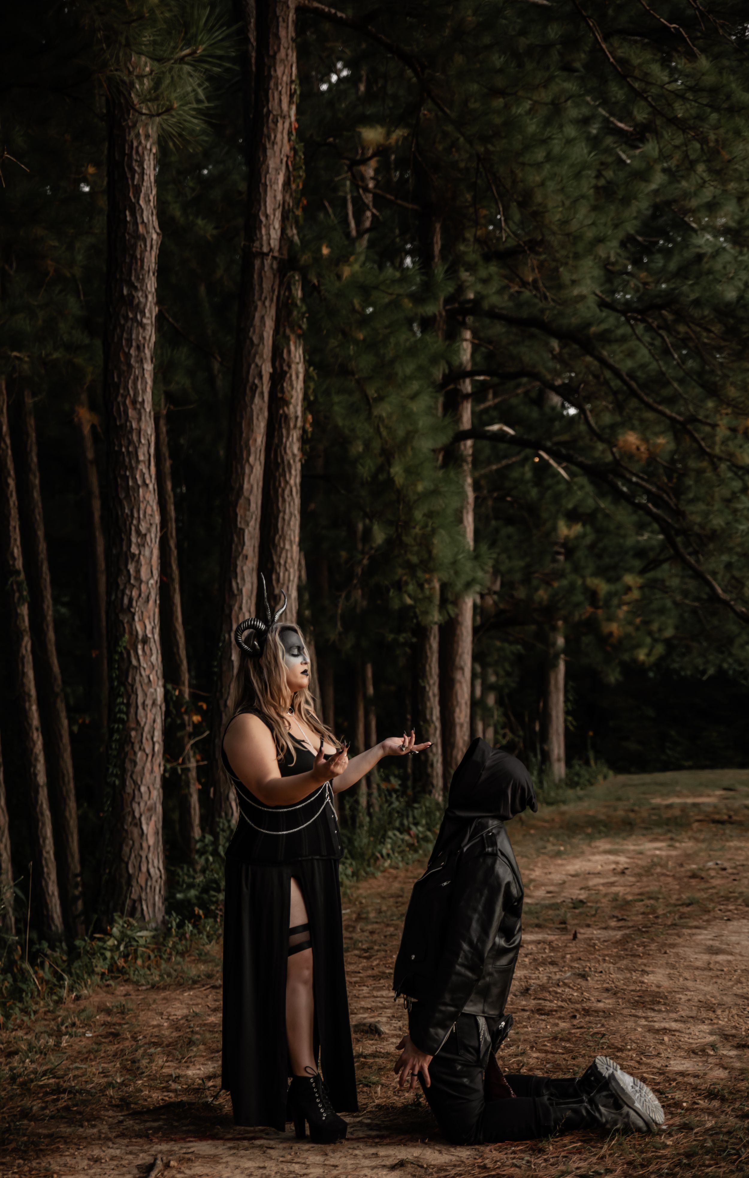 Masked figures in dark clothing create mysterious scene among tall pine trees.