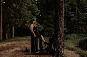 Atmospheric forest scene with two figures in dark clothing and masks posed near pine trees.