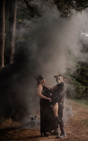 Ethereal forest photoshoot with smoke effects and two figures in gothic costumes and masks.
