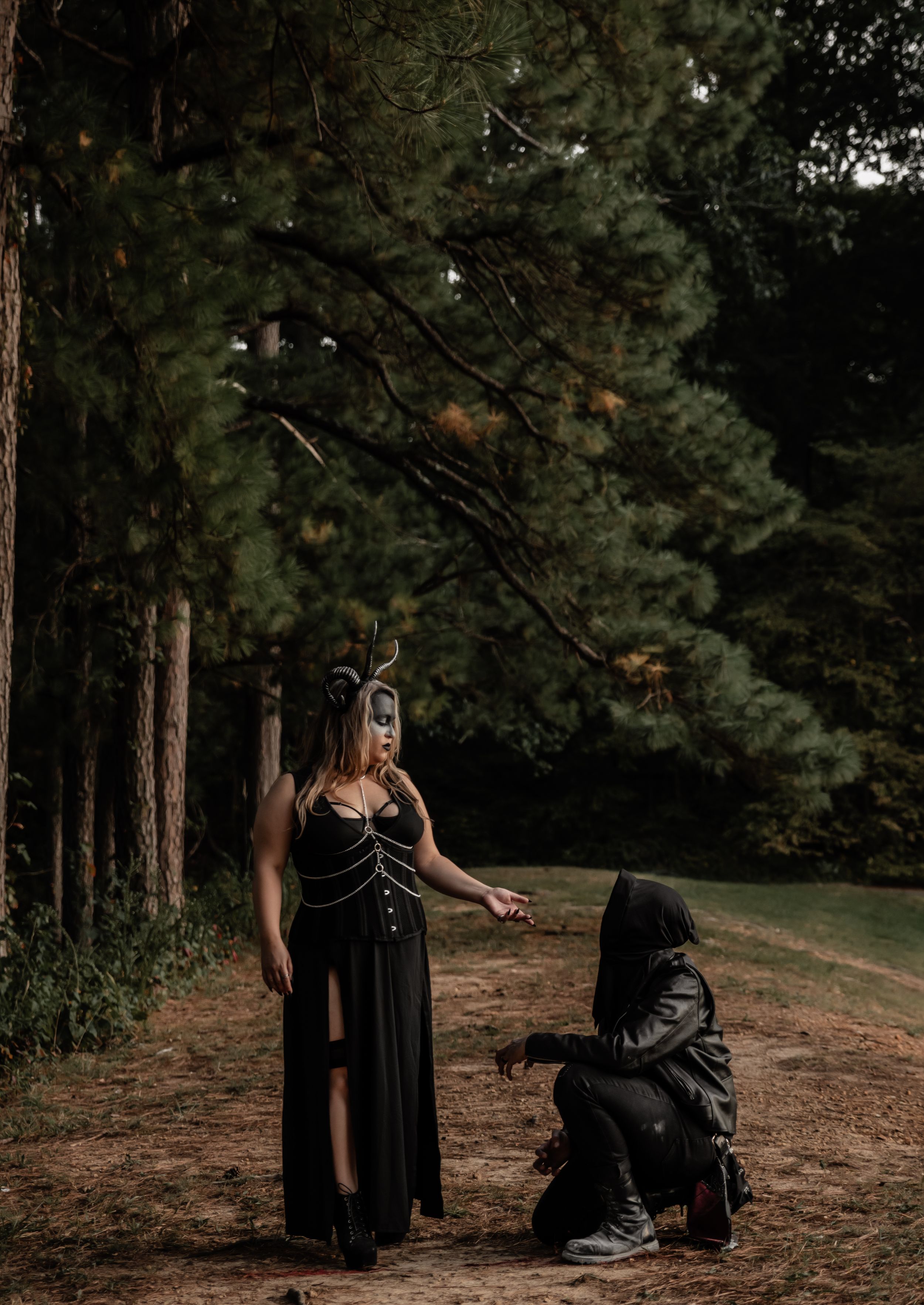 Dramatic forest photoshoot with gothic costumes and masks creating an eerie atmosphere.