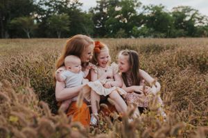 Family sitting together in a field of tall grass during golden hour.