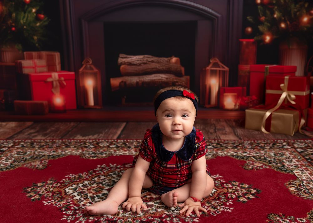 baby girl wearing a christmas red dress, fireplace, red traditional carpet, lanterns, christmas tree, christmas lights