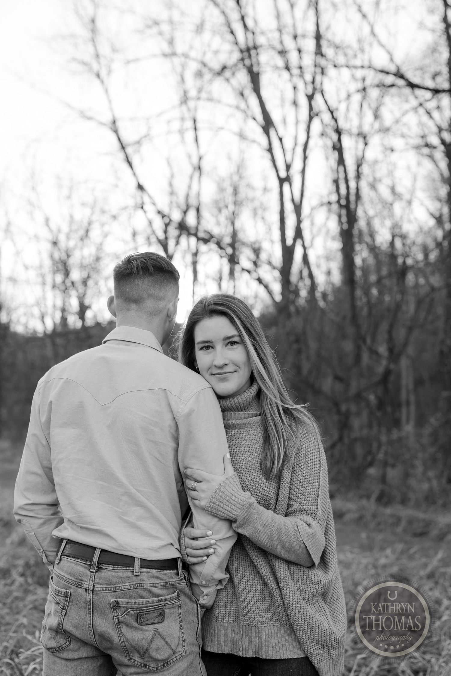 A black and white portrait captures a couple in a candid moment outdoors during fall.