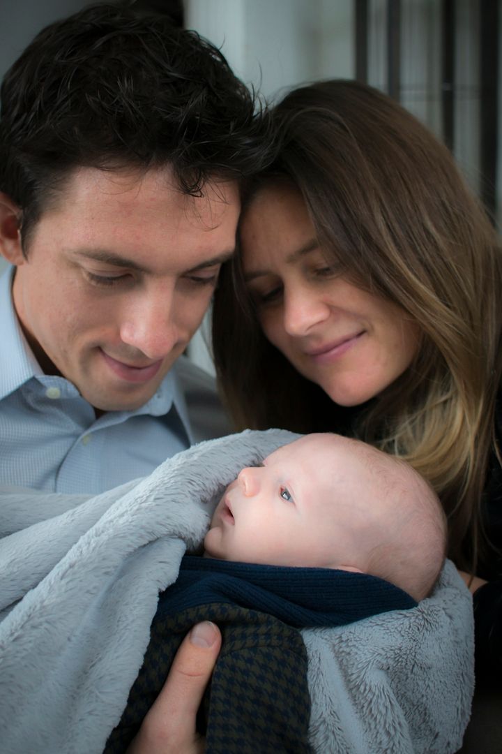 Parents holding baby in blanket and looking at him adoringly