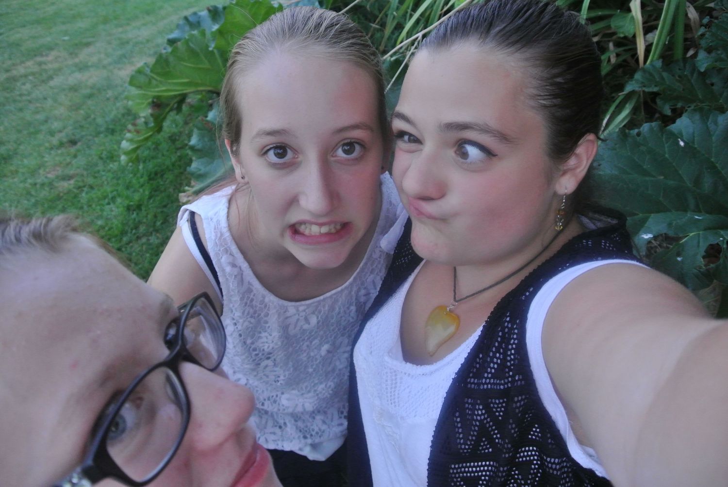Three people take a close-up selfie outdoors on a sunny day.
