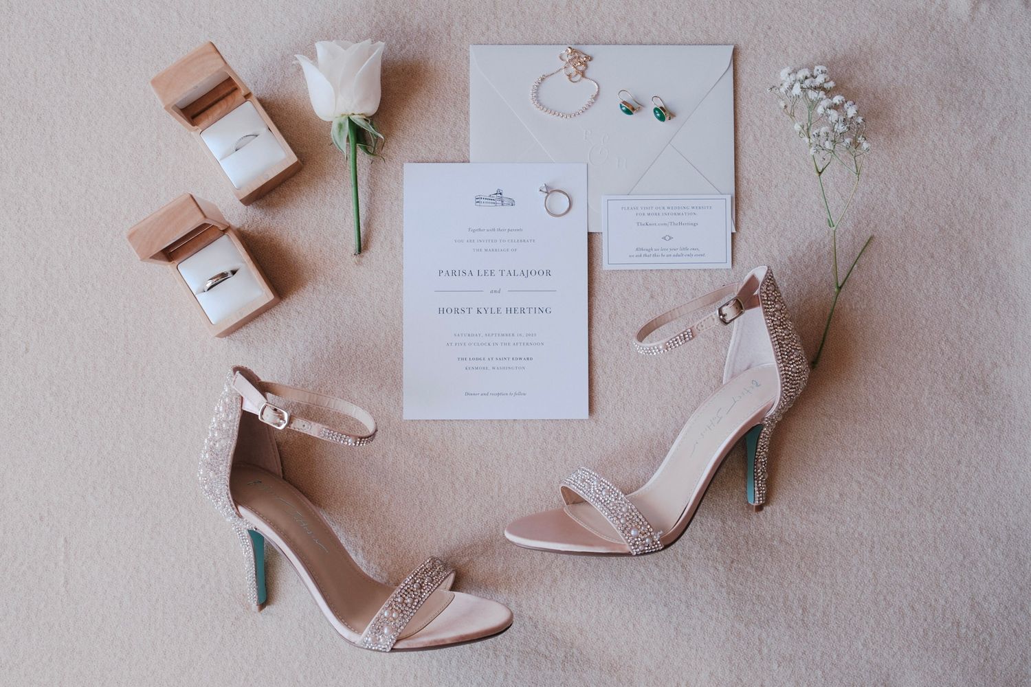 Detail shot of wedding invitation, engagement rings, and bridal shoes