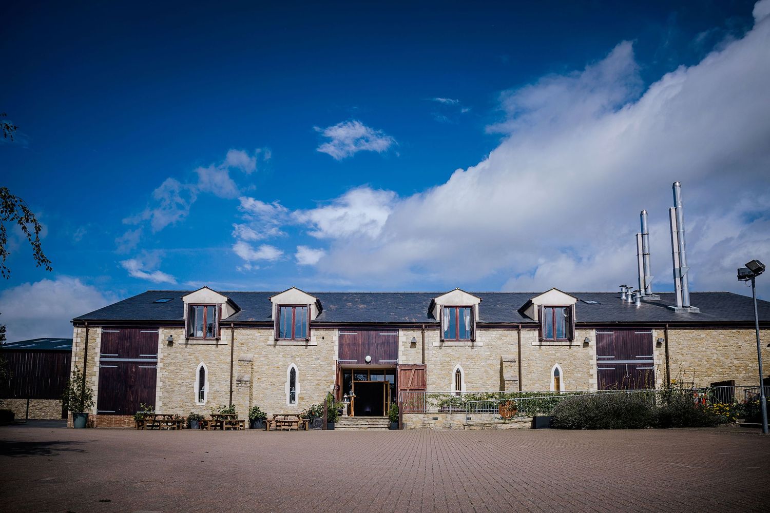 Modern stone and brick building facade with dormer windows under blue sky.